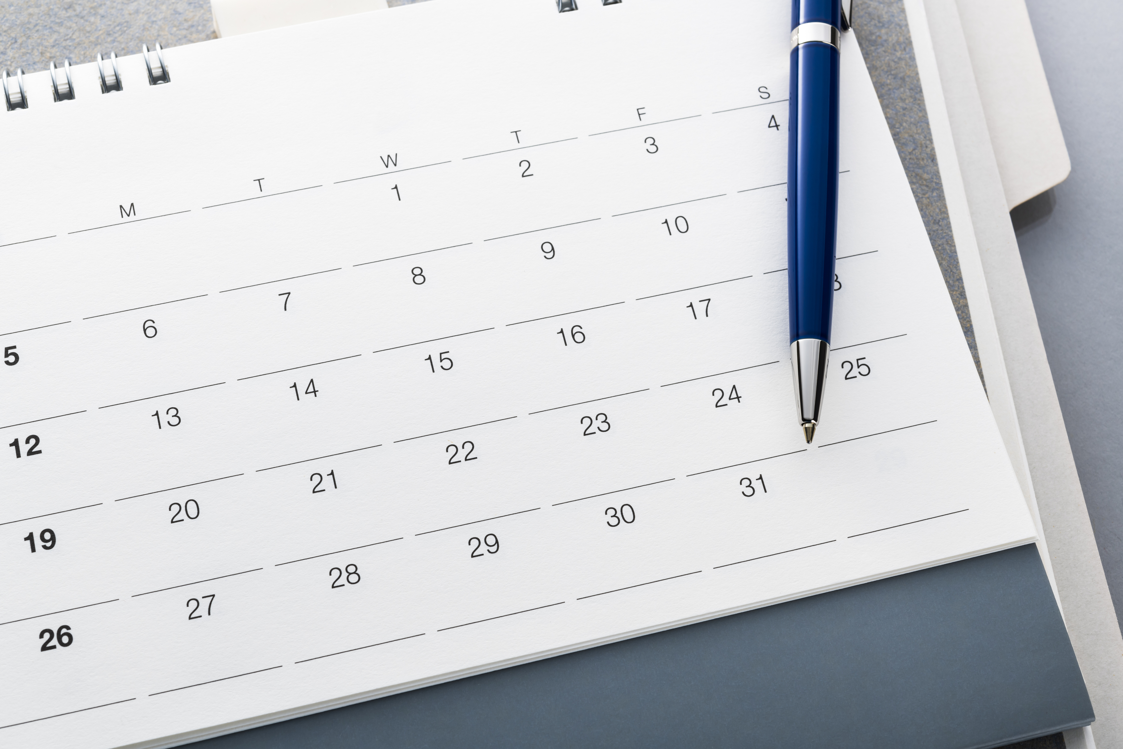 White calendar with a blue pen on top